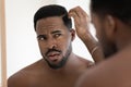 Close up anxious unhappy African American man checking hair
