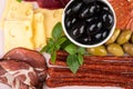 Close-up of an appetizer of olives and olives, basil and cheese, thin sausages and cuts of pork neck Royalty Free Stock Photo