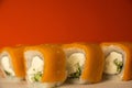 Close-up of an appetizing, freshly cooked set of sushi made from fish, cucumber, cheese sauce on a bright orange background. Sushi