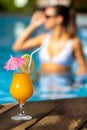 Close up appetizing fruit cocktail with out of focus woman in swimming pool