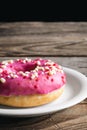 Close-up, appetizing pink donut on a wooden background.