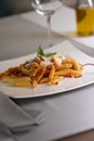 Close up of an appetizing plate of macaroni with bolognese sauce and grated cheese.