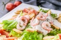 Close-up appetizing salad with shrimp, lettuce, cheese, avocado and crackers on a white plate. Delicious and healthy seafood Royalty Free Stock Photo