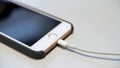 Close up of the apple iphone with the charging cable lying on the white table. Media. Process of charging of a modern