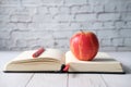 Close up of apple on and pencil on open book on table