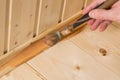 Close-up, applying dark varnish on a wooden baseboard interior