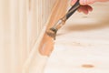 Close-up applying dark varnish on a wooden baseboard of an interior floor