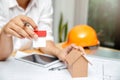 Close up of architect hands holding living house model above blueprint on table. architectural concept