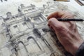 Closeup of an architects hand drawing a detailed building facade on drafting paper architectural tools in view