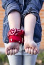 Close up of the arms of an unrecognizable person with a red scarf tied over one of the wrists. Concept of feminism, equality and