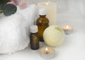 Close up aromatherapy concept with essential oil bottle, bath bomb, burning candles on light background. Royalty Free Stock Photo