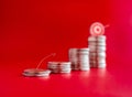 Close-up arrow line draw jumping to the goal target on the top of coin stacks, graph steps on red background.