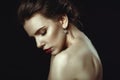 Close up art portrait of a woman with perfect make up and naked shoulders embracing herself with closed eyes