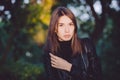 Close up art portrait of a young pretty brunette woman posing outdoors in black leather coat in golden sunlight evening spot Royalty Free Stock Photo