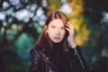 Close up art portrait of a young pretty brunette woman posing outdoors in black leather coat in golden sunlight evening spot Royalty Free Stock Photo