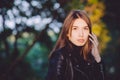 Close up art portrait of a young pretty brunette woman posing outdoors in black leather coat in golden sunlight evening spot Royalty Free Stock Photo