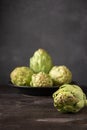 Close-up of artichokes on wooden table, with selective focus, dark background Royalty Free Stock Photo