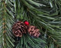 Close up of artificial pine cones and red berries surrounded evergreen branches for the Christmas season