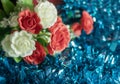Close up of artificial red and white rose flowers on blue tinsel background. Selective focus Royalty Free Stock Photo