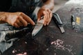 Close-up: artisan sculptor artist sharpening a blade on a sharpener in a workshop