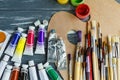 Close up of artist paint brushes, palette and watercolors on grunge gray wooden background.