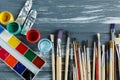 Close up of artist paint brushes,  palette and watercolors on grunge gray wooden background. Set of multicolored paints Royalty Free Stock Photo