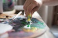 close-up of an artist& x27;s palette with paints and a hand with a tube of paint. Mixing oil paints for painting and brush Royalty Free Stock Photo