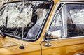 Close up artistic style view of old yellow vintage car front window wheel and antenna outdoors in summer. Royalty Free Stock Photo