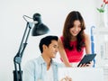 Close-up Asian business couple, young man and woman, colleagues using tablet and laptop computer. Royalty Free Stock Photo