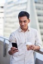 A close up of an Asian businessman on a coffee break on his phone outside Royalty Free Stock Photo