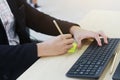 Close up on asian businessmen hands typing Keyboard and writng with pencil on yellow paper on computer desk. Royalty Free Stock Photo