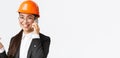 Close-up of asian businesswoman manage enterprise, engineer in safety helmet and suit having phone conversation, calling Royalty Free Stock Photo