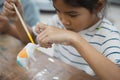 Close up asian child girl is concentrating to paint on small ceramic elephant with oil color. Royalty Free Stock Photo