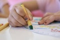 Close up of Asian child girl is drawing with crayon on white paper at home.