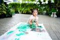 Close up Asian child girl sit down on rip canvas on tile floor on blurred garden. Royalty Free Stock Photo