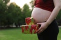 Close-up Asian Chinese pregnant woman`s belly present gift wrap beside belly Merry Christmas holiday concept expecting baby