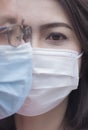 Close up of Asian couple faces in medical face masks, focus at woman eyes looking at camera