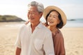 close up of asian elderly carefree couple standing on the beach and smiling at you happily in sunset background Royalty Free Stock Photo