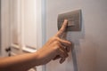 Asian female right hand is turning off on grey light switch Royalty Free Stock Photo