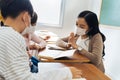 Close-up of Asian female teacher wearing face mask in school building tutoring a primary student children. Elementary Royalty Free Stock Photo