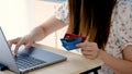 Close Up Asian hand girl, is ordering online through a laptop computer, holding three credit cards in her hand, in order to choose Royalty Free Stock Photo