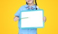Close-up Asian little girl holding pencil pointing on blank white blackboard isolated over yellow background. Schoolgirl and Royalty Free Stock Photo
