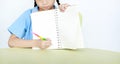 Close-up Asian little girl in school uniform show writing on blank notebook sitting at desk over white background Royalty Free Stock Photo