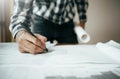 Close-up of asian male civil engineer working on blueprint architecture project on construction site at work desk in office