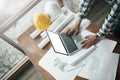 Close-up of asian male civil engineer working with drawings inspection on laptop on construction site at work desk in office