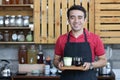 Close up asian man barista smiling holding laptop checking orders and stock behind the counter. cafe owner standing in restaurant Royalty Free Stock Photo