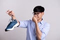 Close up asian man holding dirty stinky shoe with an expression of disgust. Healthcare concept Royalty Free Stock Photo