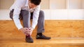 Close-up of an Asian man with leg pain due to twisted ankles while walking and holding on to