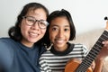 Close-up of an Asian mother and daughter taking a selfie and smiling while sitting on the sofa. The little girl holding a ukulele Royalty Free Stock Photo