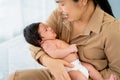 Close up Asian mother hold newborn baby and sit on bed in bedroom with day light and take care also look with love and happiness